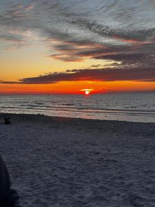 a sunset on the beach with the sun setting at Domki ALKANA - domek 3 in Nowęcin +5 photos