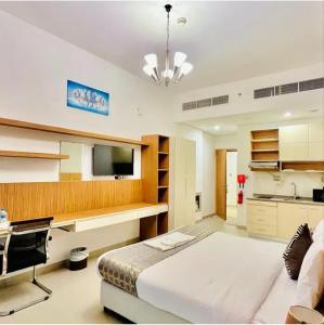 a bedroom with a bed and a desk and a television at The Saj Hotel Apartments in Ras al Khaimah