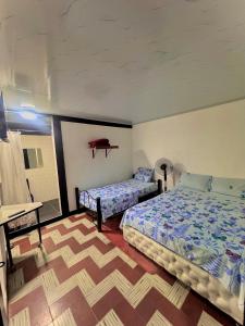 a bedroom with two beds and a table in it at Hotel Bachue Ibagué in Ibagué