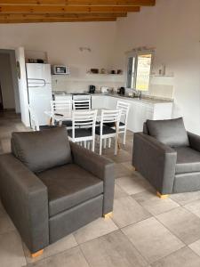 a living room with two couches and a kitchen at Complejo Aiken in Trevelín