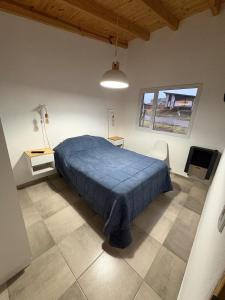 a bedroom with a bed with a blue blanket on it at Complejo Aiken in Trevelín