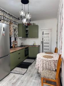 a kitchen with green cabinets and a table and a refrigerator at Dream Guest House in Bosteri