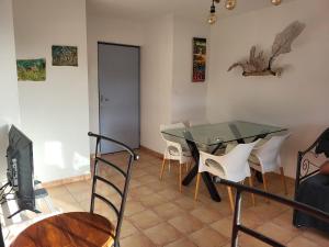 a dining room with a glass table and white chairs at Résidence les Antillannes in Gourbeyre