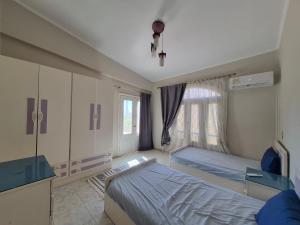 a hospital room with two beds and a window at Coastal Comforts at Casabianca in Dawwār Muḩammad Abū Shanab +9 photos