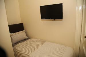 a small bedroom with a bed and a flat screen tv at Victorin House - All rooms are EN-SUITE in Portsmouth