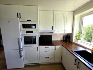 a kitchen with white cabinets and white appliances at Unique Villa by a beautiful lake in Omberg +16 photos