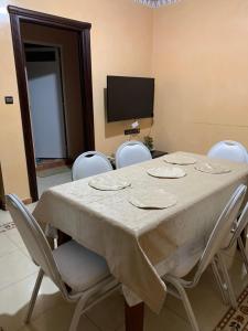 a dining room table with white chairs and a television at Rayan in Tangier