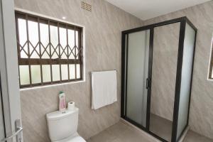 a bathroom with a toilet and a glass shower at Chic Modern Escape in Lusaka +15 photos