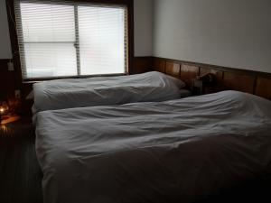 two unmade beds in a room with a window at 卌屋 shioya in Gujo