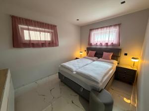 a small bedroom with a bed and two windows at Guest Apartman in Tiszakécske