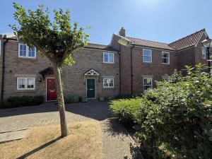 a brick house with a red door and a tree at Sea Esta, The Bay, 2 bedrooms, patio garden, parking nearby, 2 dogs welcome in Filey