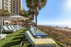 a row of chaise lounge chairs on the beach at The Strand - A Boutique Resort in Myrtle Beach