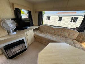 a living room with a couch and a flat screen tv at Sweet Caravan - Hemsby in Hemsby