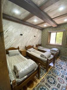 a room with three beds in a brick wall at Ikhtiyor guest house with mountainiring hiking horse riding serivices in Yukary-Ukhum