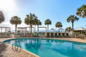 a swimming pool with chairs and palm trees and the ocean at The Strand - A Boutique Resort in Myrtle Beach