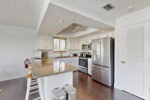 a kitchen with white cabinets and a stainless steel refrigerator at Spring Oasis in Anna Maria