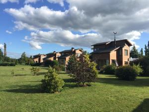 a group of houses in a field with trees at Cabañas Portal de las Rosas in Puerto Varas