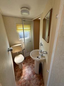 a small bathroom with a toilet and a sink at Sweet Caravan - Hemsby in Hemsby +31 photos