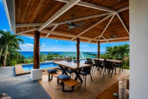 an outdoor patio with tables and chairs and a pool at Lodge Las Estrellas de Samara - Ocean View in Sámara
