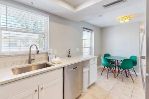 a kitchen with a sink and a table with green chairs at Gertie's Lime House in Holmes Beach +23 photos