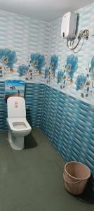 a bathroom with a toilet and a wall with flowers at Bagan Bilas Homestay in Jhilimili +33 photos