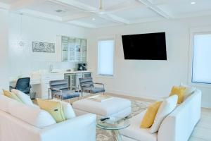 a white living room with a white couch and a tv at Gulf View Estate in Anna Maria