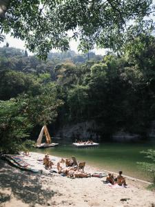 a group of people on a beach with a boat in the water at Rio Hostel Buritaca in Buritaca +54 photos