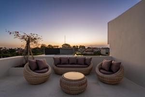 a group of chairs and a table on a balcony at Casa Infinity Villa 2 - Oasis 3BR & Ocean View by BaliSuperHost in Mengwi