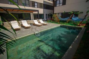 a swimming pool with chairs and a hammock next to a building at Blend Coliving One - 1 in Ribeirão Preto