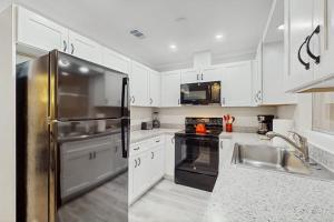 a kitchen with white cabinets and a stainless steel refrigerator at Mint Green Getaway in Holmes Beach
