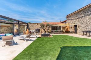 a backyard with a lawn and a stone building at L'Apothicaire 2 Chambres - Piscine in Montaigu-Vendée