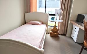 a small bedroom with a bed and a window at The Fifth Season in Unanderra