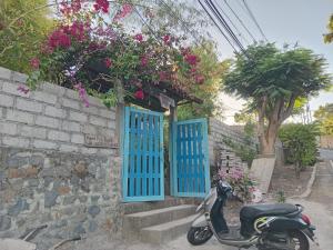 a scooter parked next to a brick wall with blue doors at Nyoman Guest House 1 in Ambat