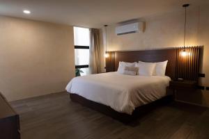 a hotel room with a large bed with white sheets at Moreira Hotel Boutique in Mérida