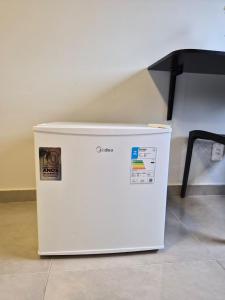 a white refrigerator sitting on the floor next to a chair at CaisSuites in Cabo Frio