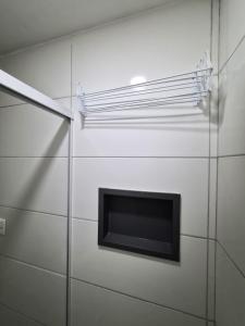 a glass wall with a tv in a bathroom at CaisSuites in Cabo Frio