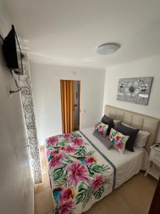 a bedroom with a bed with a flower blanket at Casa Prédio triplex - Faneca Apartamentos in Nazaré