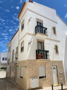 a white building with black balconies on it at Casa Prédio triplex - Faneca Apartamentos in Nazaré