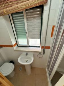 a bathroom with a toilet and a sink and a window at Casa Prédio triplex - Faneca Apartamentos in Nazaré