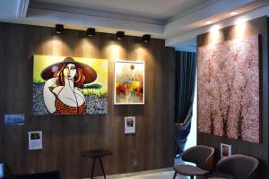 a wall with a painting of a woman in a hat at Sandri Palace Hotel in Itajaí