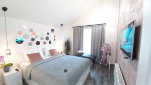 a white bedroom with a bed and a tv at Chalet Terra Transfăgărășan in Cerbureni
