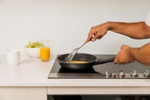 a person cooking food in a frying pan on a stove at Quest on Wickham Terrace in Brisbane