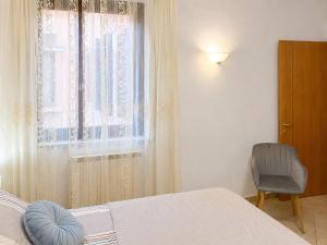 a bedroom with a bed and a window with a chair at Casa Iris in Montepulciano