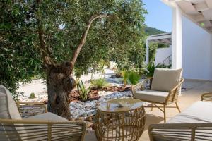 a patio with a tree and chairs and a table at Oasis deluxe apartments in Skala Rachoniou