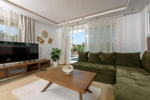 a living room with a green couch and a television at Oasis deluxe apartments in Skala Rachoniou