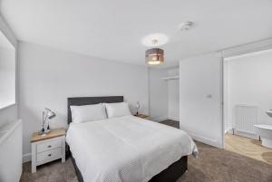 a white bedroom with a bed and a sink at Stoney suites in Stonehaven