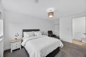 a white bedroom with a large bed and a chair at Stoney suites in Stonehaven