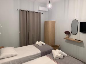 a bedroom with two beds and a mirror and a tv at Sidari Centre Apartments in Sidari