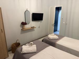 a room with two beds and a mirror and a tv at Sidari Centre Apartments in Sidari