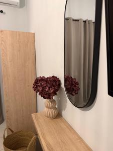 a mirror and a vase with flowers on a table at Sidari Centre Apartments in Sidari